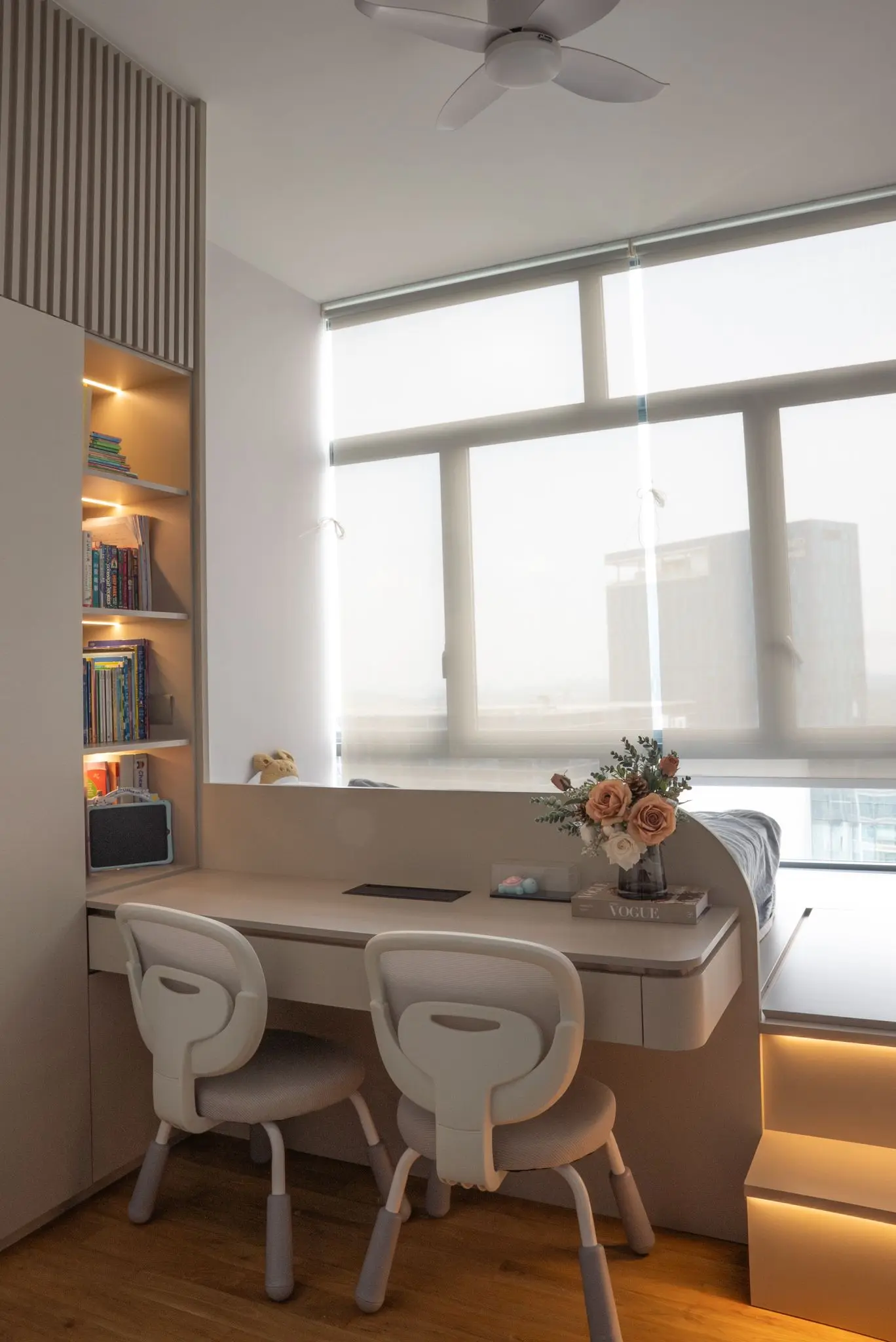 Modern desk setup with bookshelf and window view