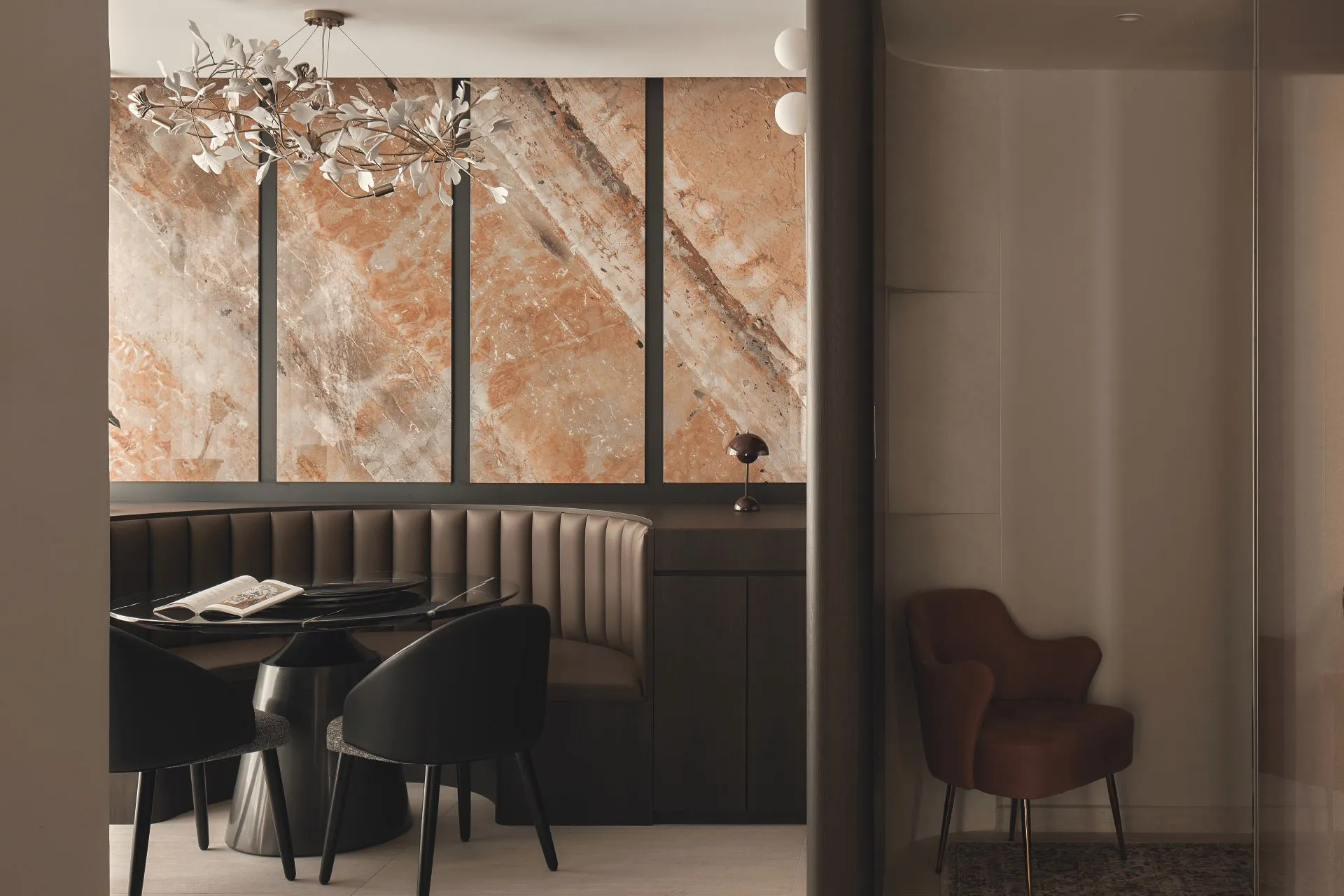 Modern dining area with marble wall and chandelier.
